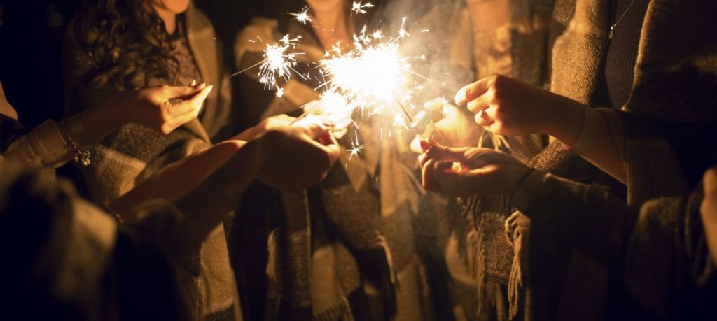 Group of people standing in a circle holding sparklers